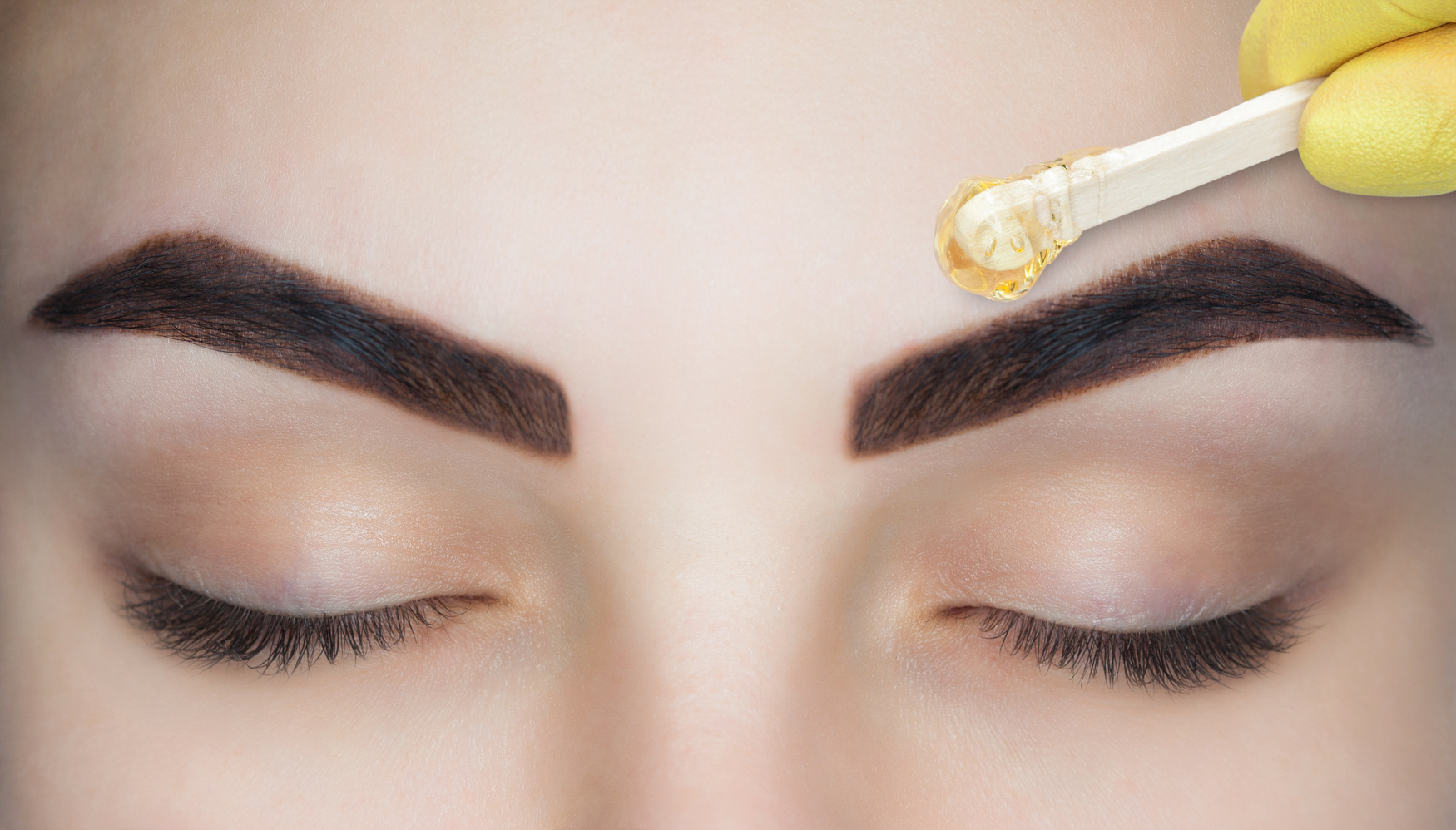 The make-up artist plucks her eyebrows, before the procedure of permanent make-up in the beauty salon.